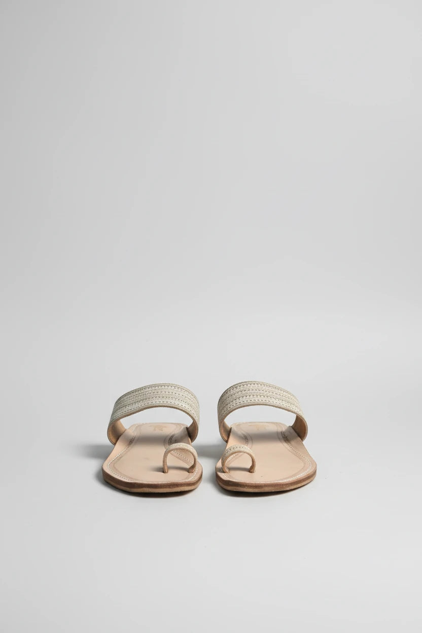 Pair of sandals on a mat with potted plants in the background
