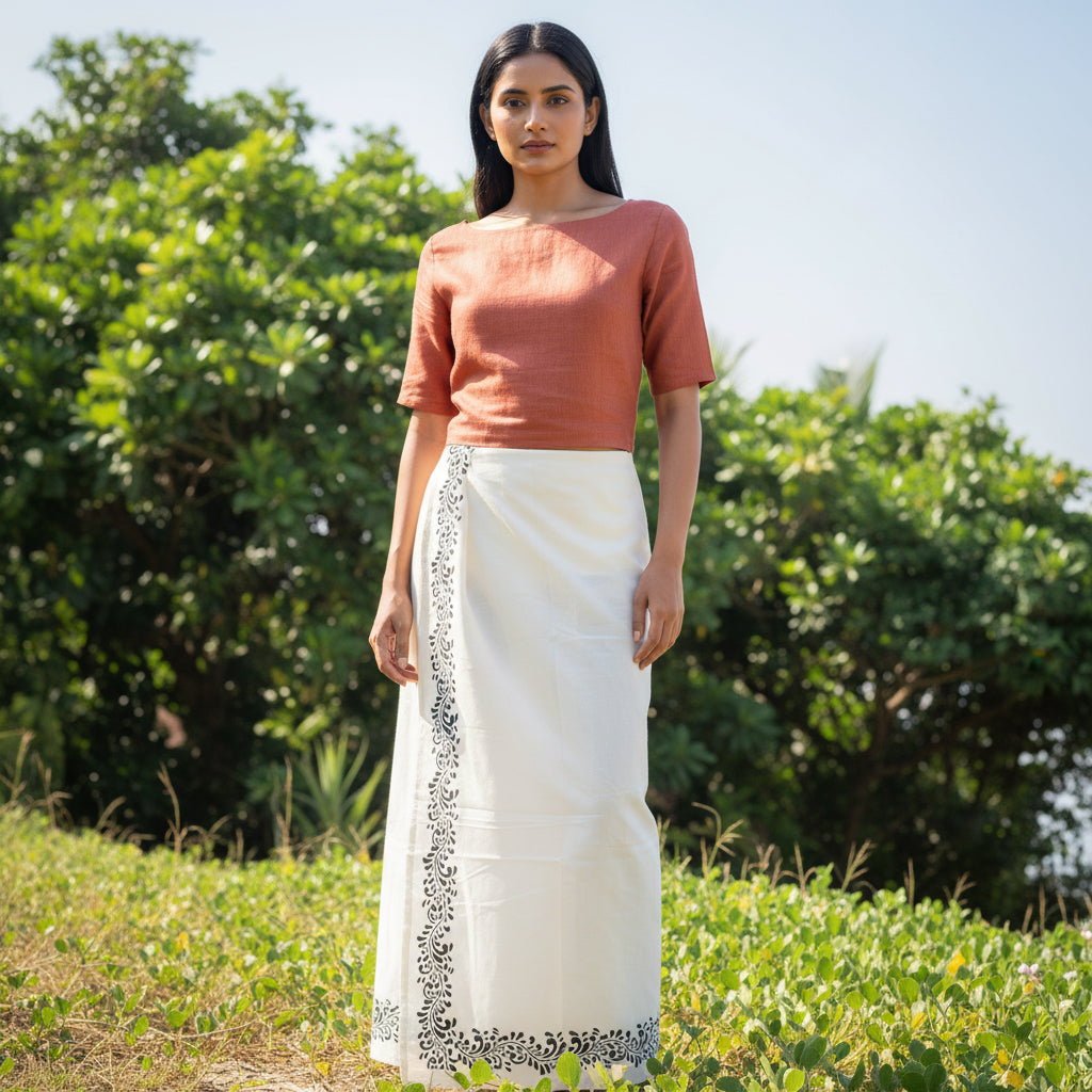 Person wearing a white dhoti with black embroidery standing in a field.