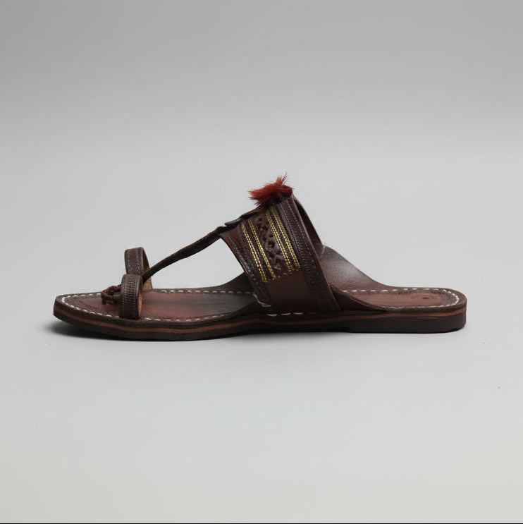 Pair of brown sandals with decorative elements on a grass background