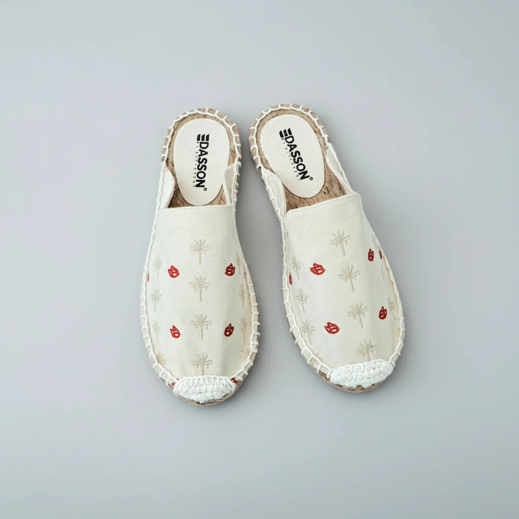 Pair of white slippers with red floral patterns on a white background