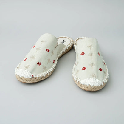 Pair of white slippers with red floral patterns on a white background