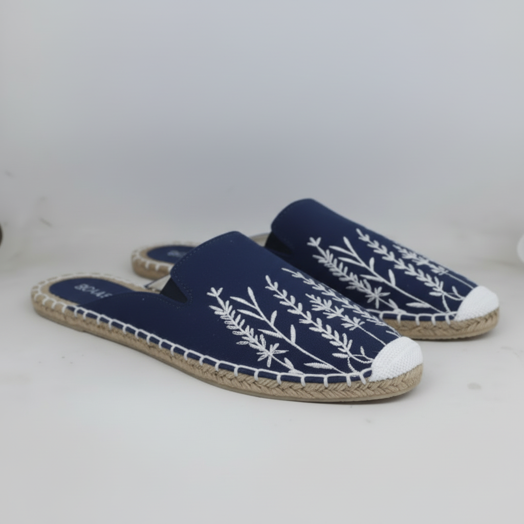 Pair of blue espadrille sandals with white floral patterns on a white background