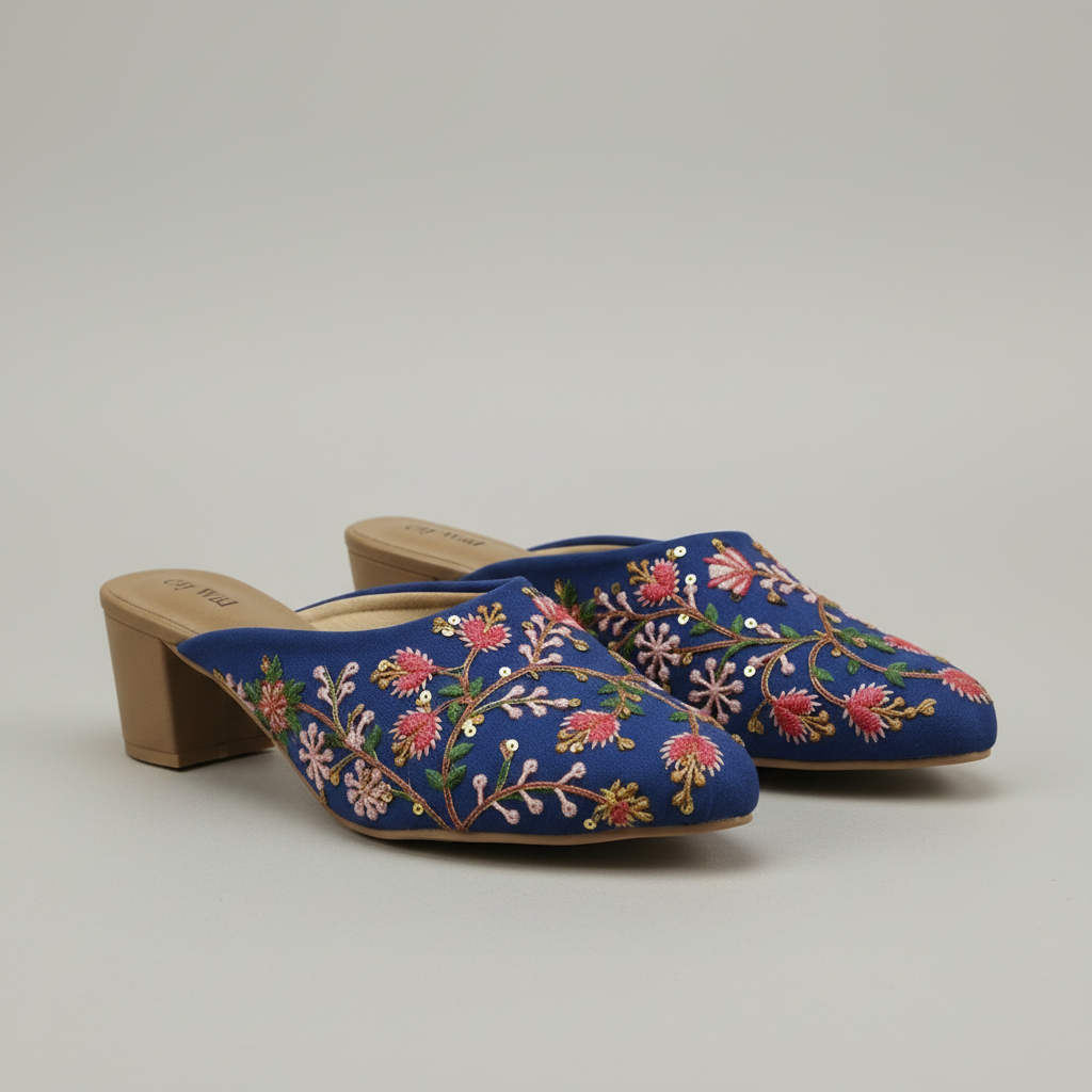 Blue embroidered slippers on a wooden floor with a plant in the background