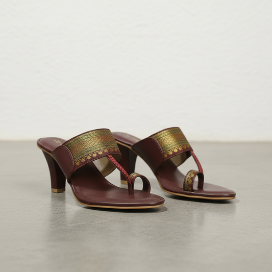 Pair of high-heeled sandals with gold accents on a neutral background