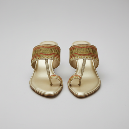 Gold sandals with jewelry and flowers on a textured surface