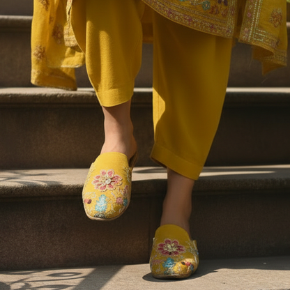 Person wearing a yellow traditional outfit with floral patterns on steps outdoors.