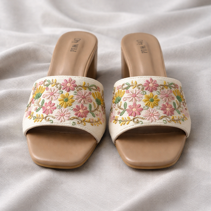 Pair of floral embroidered sandals on a light fabric background
