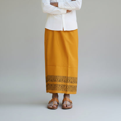 Person wearing a mustard yellow skirt with a white top on a gray background