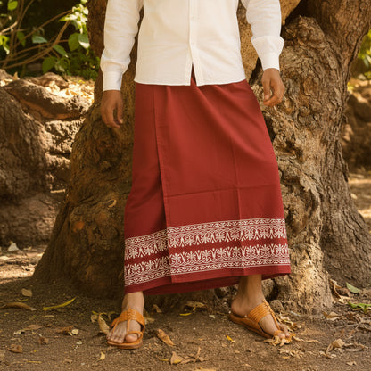 Person wearing a red skirt with white embroidery and a white shirt, standing against a natural background.