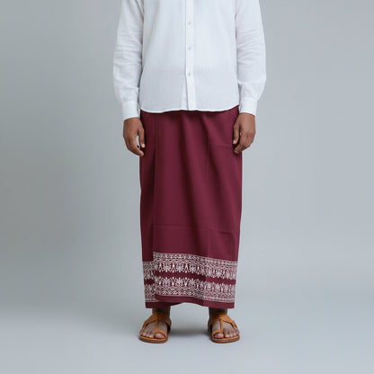 Person wearing a white shirt and maroon skirt with elephant pattern on a gray background