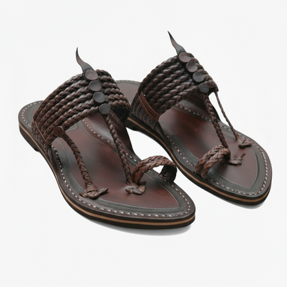 Pair of brown Just Kolhapuris by niira with braided straps on a white background