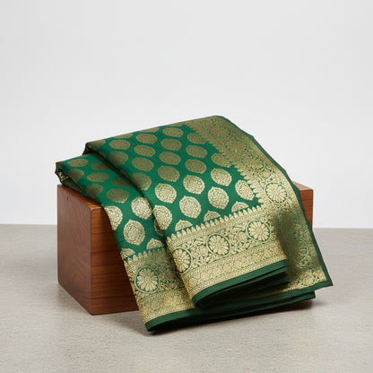 Green and gold saree with intricate patterns on a wooden surface