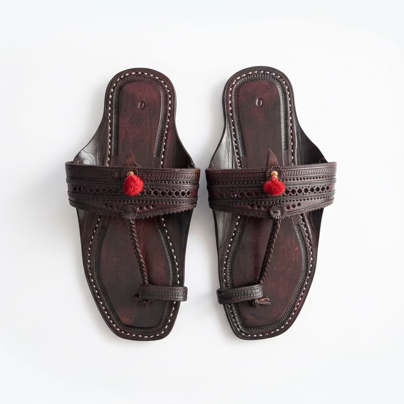 Pair of black sandals with red accents on a light tiled floor