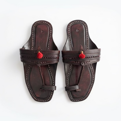 Pair of black sandals with red accents on a light tiled floor