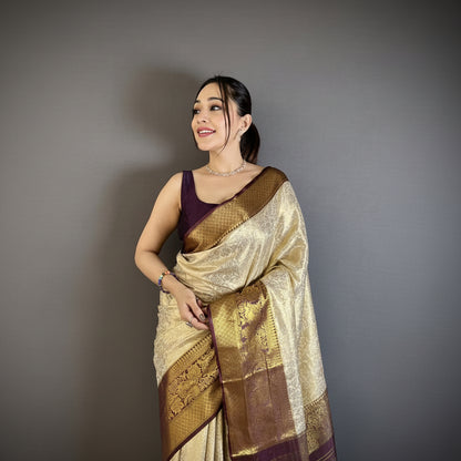 Woman wearing a gold saree with a purple blouse against a gray background