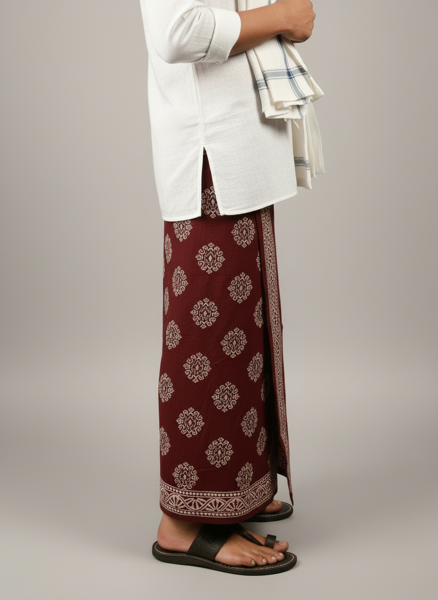 Person wearing a white shirt and maroon patterned dhoti|lungi|wrap on a plain background