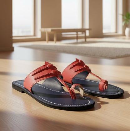 A pair of women's Kolhapuri chappals with a brown strap and black base, placed on a carpeted floor.