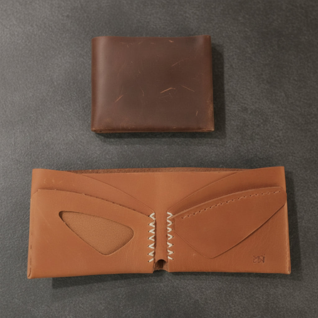 Two brown leather wallets on a light wooden surface
