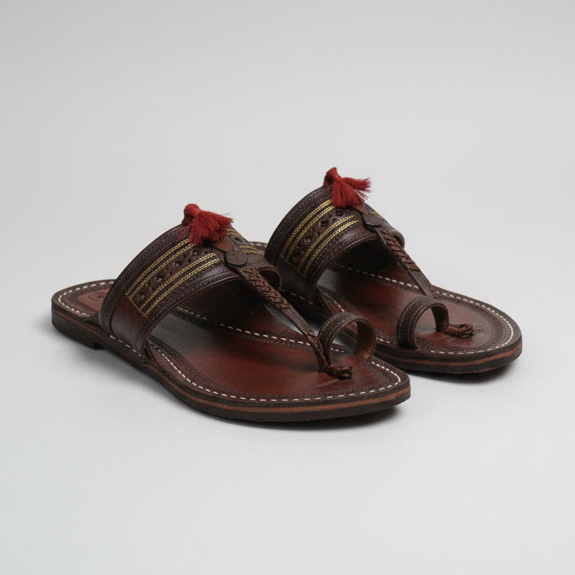 Pair of brown sandals with decorative straps on a white background