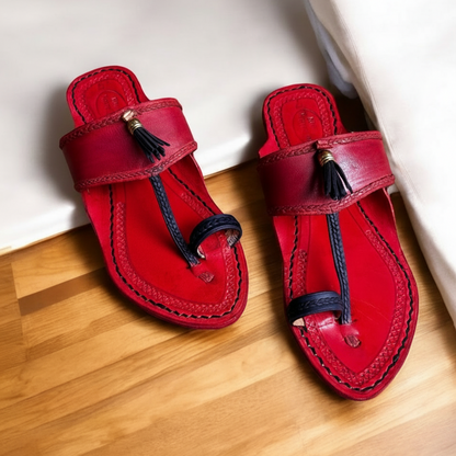 Pair of red sandals with tassels on a wooden floor, featuring the Khaal Karagin brand.
