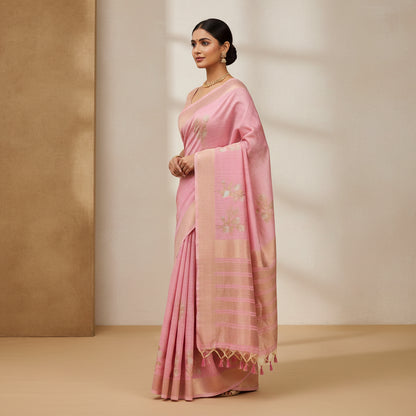 Pink and brown patterned fabric with tassels on a textured surface with green leaves.