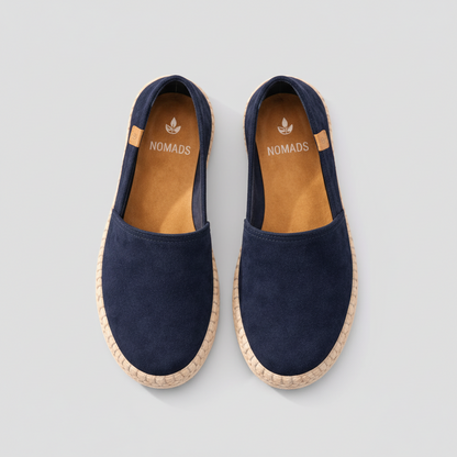 Pair of navy blue espadrilles with 'Nomads' branding on a textured surface.