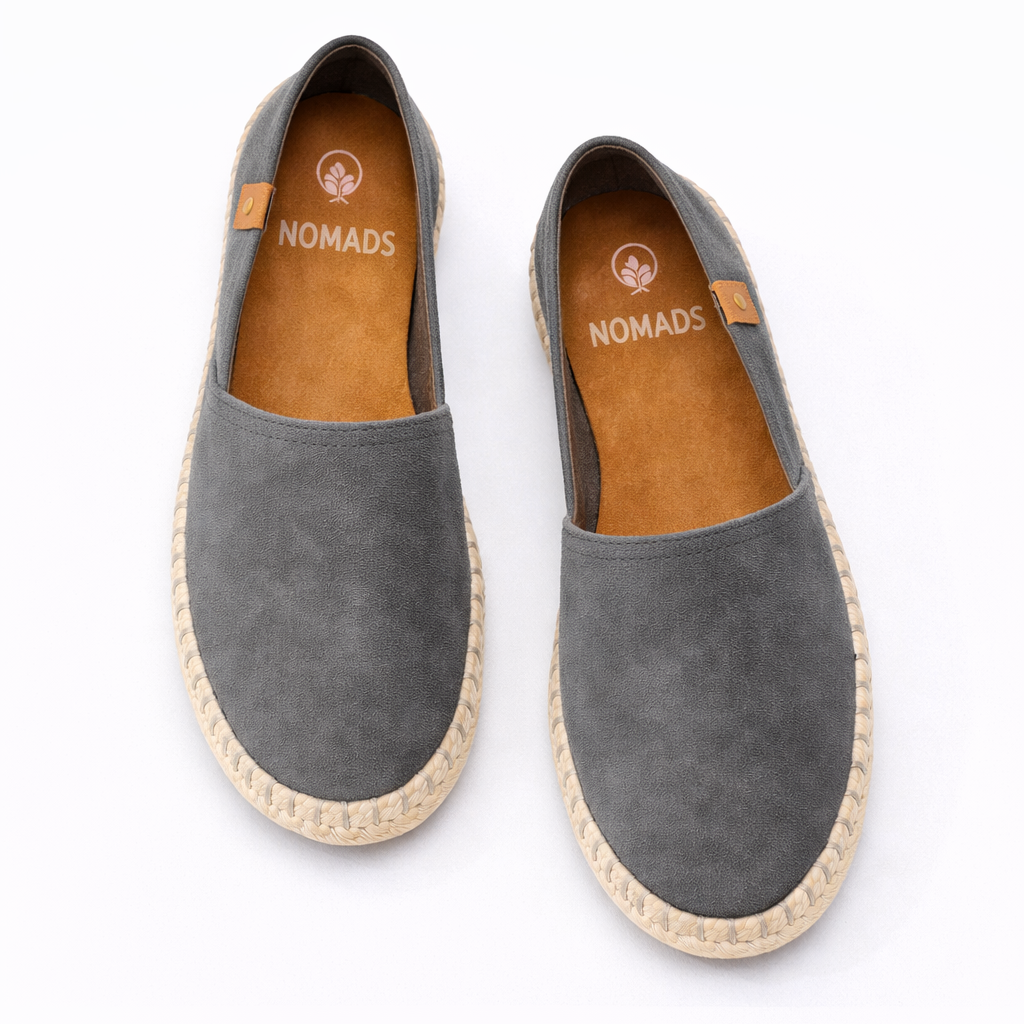 Pair of gray espadrilles with 'Nomads' branding on a white background