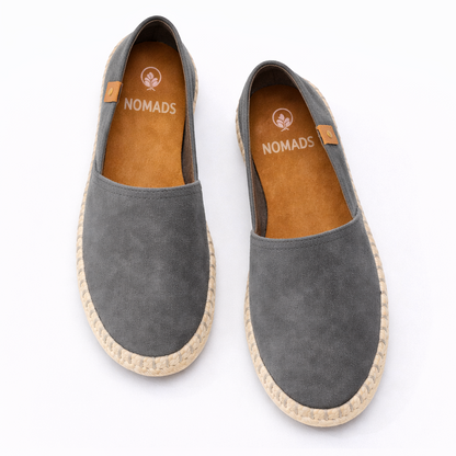 Pair of gray espadrilles with 'Nomads' branding on a white background