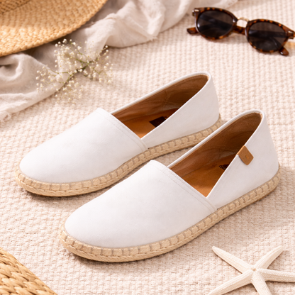 White espadrille shoes on a textured surface with a hat, sunglasses, and starfish.