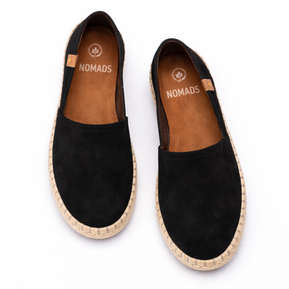 Pair of black espadrilles with 'Nomads' branding on a white background