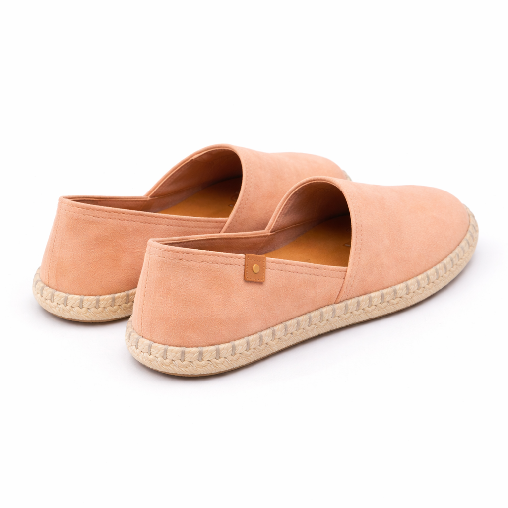 Pair of peach-colored espadrilles on a white background