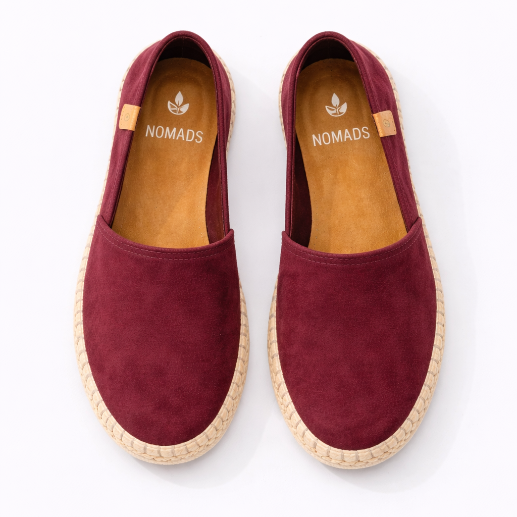 Pair of maroon espadrilles with 'Nomads' branding on a white background