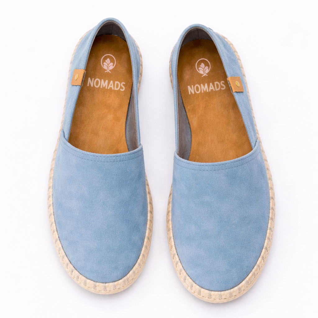 Pair of light blue espadrilles with 'Nomads' branding on a white background