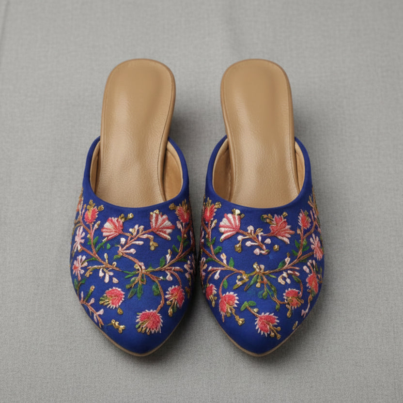 Pair of blue embroidered slippers with floral patterns on a white background
