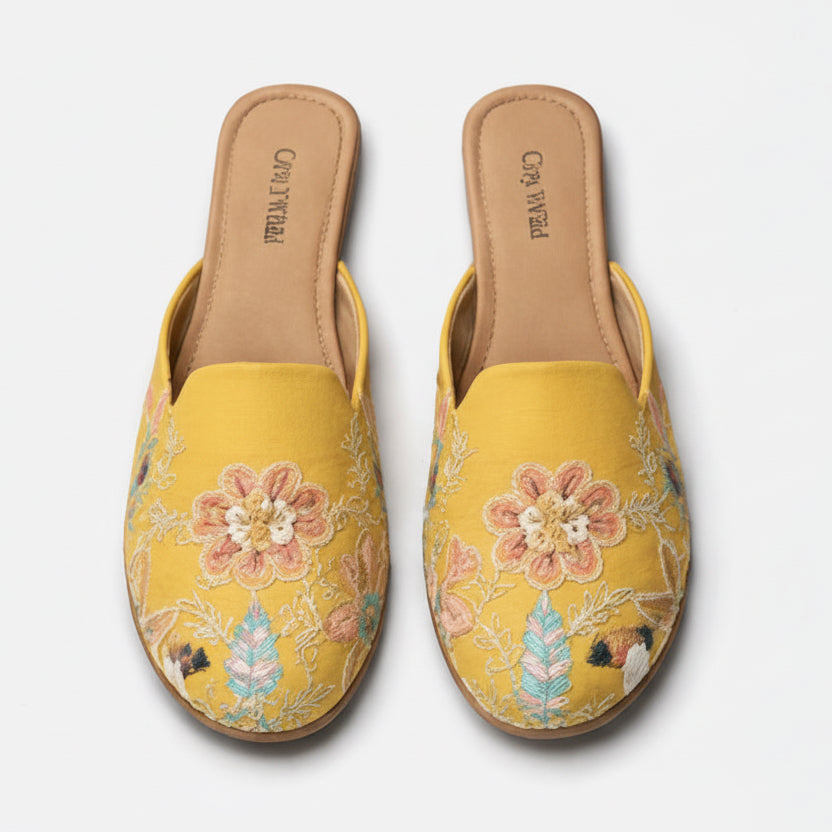 Pair of yellow embroidered slippers on a white background