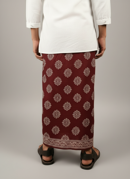 Person wearing a maroon patterned skirt with a plain white top on a light gray background